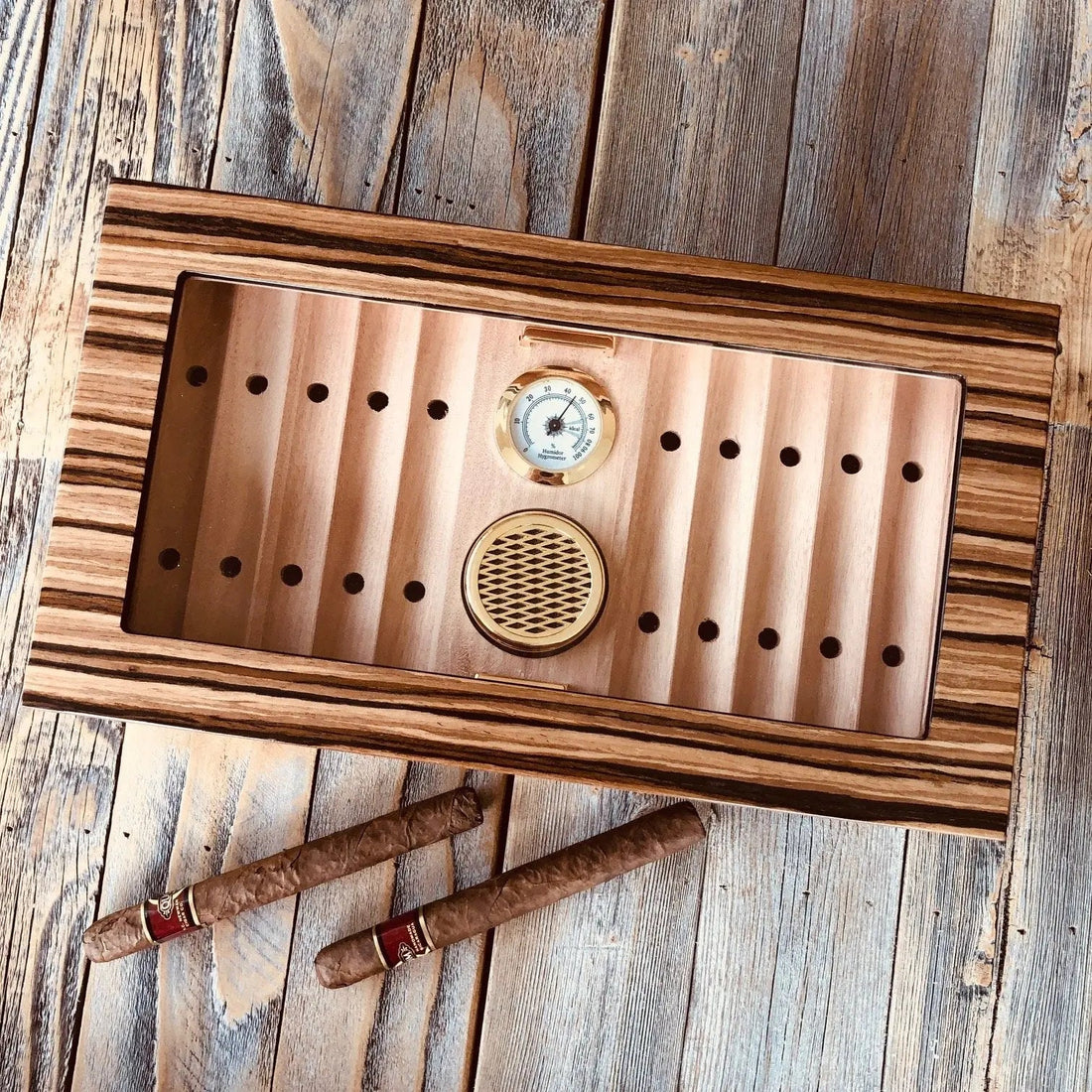 Glass top wooden desktop humidor with cigars stored inside at ideal humidity for long-term cigar storage