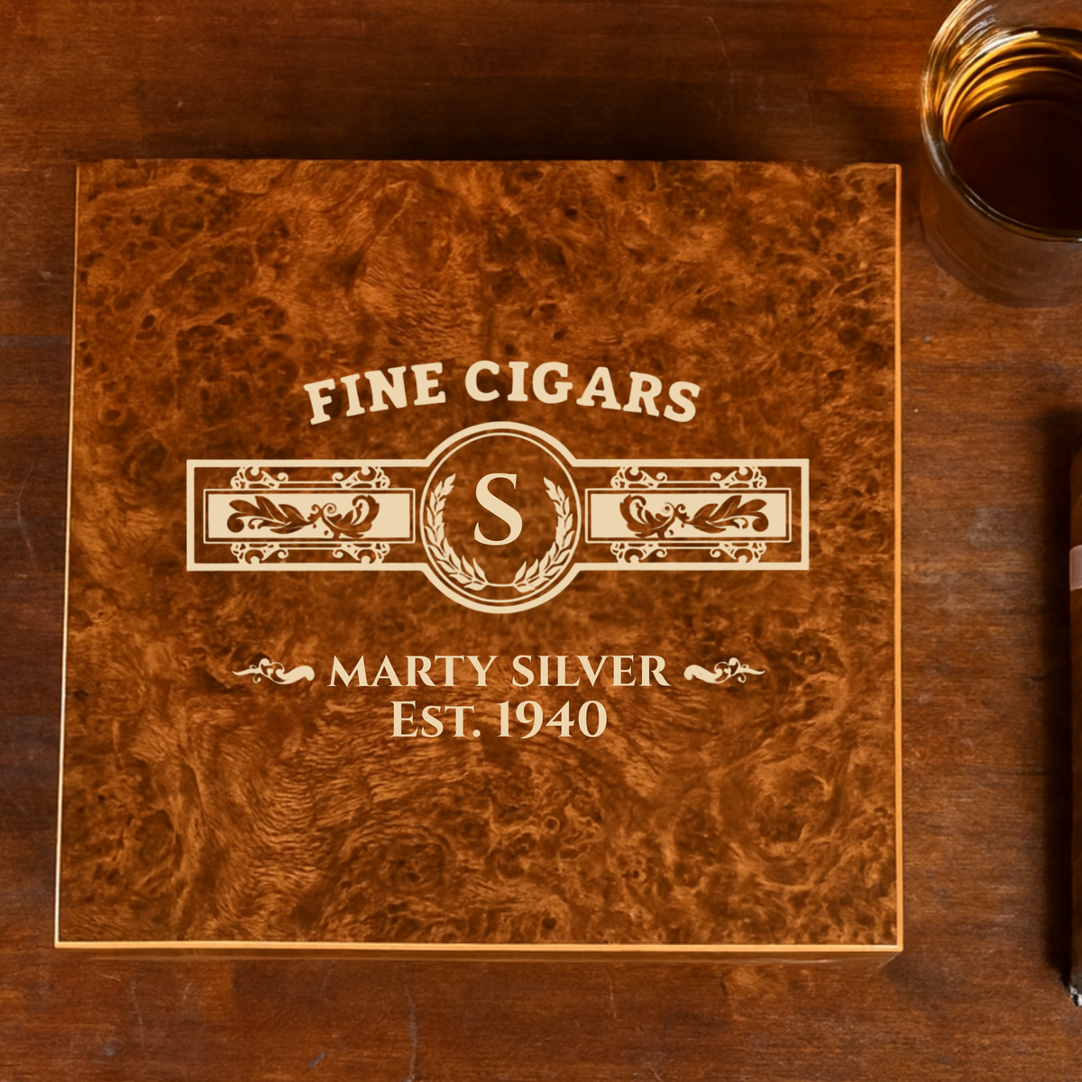 Wooden cigar humidor lid engraved with sample personalization showing initials "S" and "MARTY SILVER EST. 1940" with decorative laurel wreath border and Fine Cigars text
