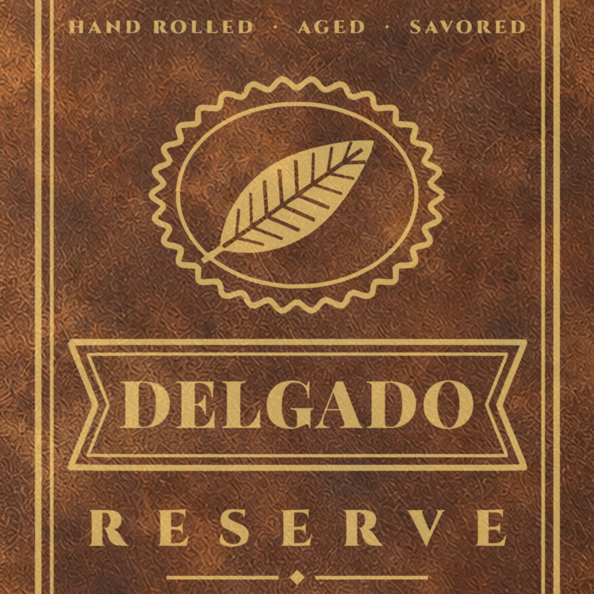 Close-up of the gold engraving on the cigar journal: a tobacco leaf crest above the cigar band with Delgado and the word Reserve